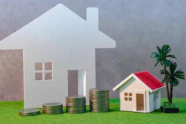 Real estate investment or Home mortgage loan rate. Property ladder concept. Coins stack and house model on green grass. Investment and business growth background
