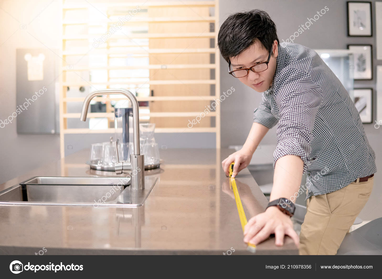 Young Asian Man Using Tape Measure Measuring Granite Countertops
