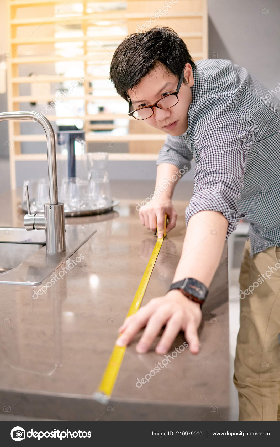 Young Asian Man Using Tape Measure Measuring Granite Countertops