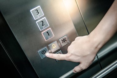 Asansör (lift) içinde açık kapı butonuna basarak erkek işaret parmağı. Makine Mühendisliği kavramı