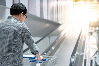 Süpermarkette ya da markette alışveriş arabasında (travelatörde) alışveriş yapan genç Asyalı adam (tramvay). Alışveriş yaşam tarzı konsepti