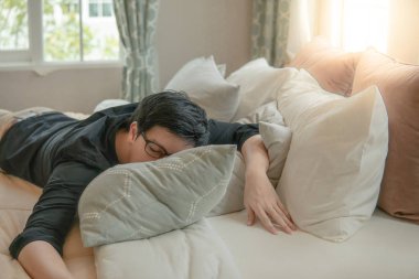 Asya genç yatak yatak odasında sabah uyku gözlük ile. Yaşam tarzı kavramı yaşayan ev