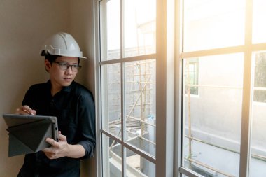 Küçük Asya mühendislik kask ve dijital tablet inşaat sahasında pencereden bakarak kullanma gözlük ile. Konut Projesi kavramı