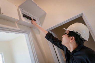 Evde kapı çerçevenin üzerine anahtarı elektrik pano Yönetim Kurulu Denetleme Genç Asyalı elektrik teknisyeni. Bakım ve kurulum elektrik sistemi
