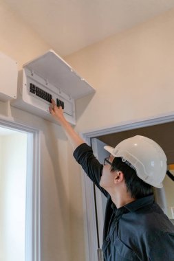 Evde kapı çerçevenin üzerine anahtarı elektrik pano Yönetim Kurulu Denetleme Genç Asyalı elektrik teknisyeni. Bakım ve kurulum elektrik sistemi