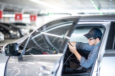 Küçük Asya gözlüklü adam ve sürücü koltuğu otopark arabasında otururken akıllı telefon Gps navigasyon uygulaması üzerinde kullanarak kap. Otomobil kavramı kentsel yaşam tarzı