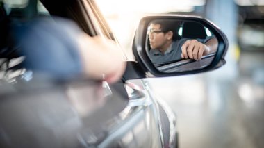 Asya auto sürücü adam kolunu araba penceresinden yaslanmış. Kanat ayna yansıması. Otomobil taşıma konsepti ile kentsel yaşam tarzı