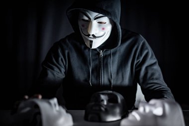 Bangkok, Tayland - 21 Eylül 2018: kapüşonlu adam masanın üzerine siyah ya da beyaz maskeleri seçme gizemli maske takıyor. Anonim sosyal maskeleme. Major depresif bozukluk. Cadılar Bayramı kavramı