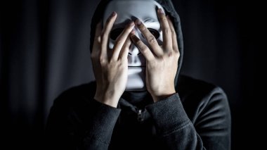 Gizemli hoody adam karanlık odada beyaz maske takıyor. Anonim sosyal maskeleme. Major depresif bozukluk ya da bipolar bozukluk. Cadılar Bayramı kavramı