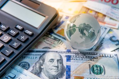 Küresel iş ve ekonomi. Dünya küre kristal cam ve çeşitli uluslararası para banknot hesap makinesi. Para birimi döviz kuru. Finansal yatırım kavramı
