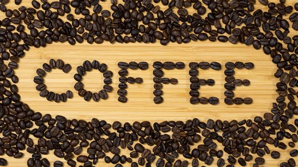 Coffee word with frame made from coffee beans on wooden background. Top view of wood table.