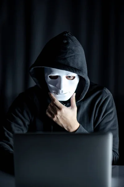 Hacker homem segurando máscara branca olhando para laptop — Fotografia de Stock
