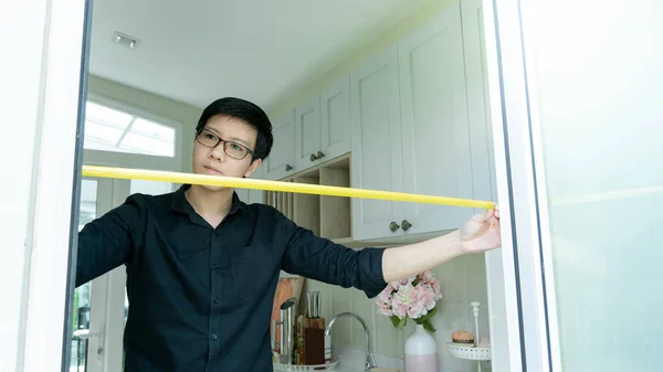 Asian man using tape measure on door frame