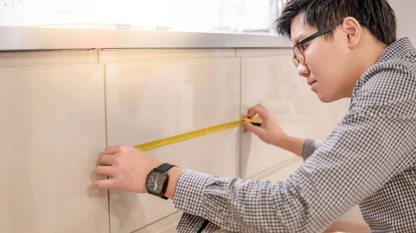 Молодой Азиат Использующий Рулетку Измерения Современного Кухонного Счетчика Выставочном Зале — стоковое фото