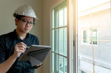 Küçük Asya mühendislik kask ve dijital tablet inşaat sahasında pencereden bakarak kullanma gözlük ile. Konut Projesi kavramı