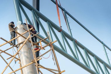 Ahşap iskele kaynak üzerinde duran erkek inşaat işçileri truss yapı inşaat sahasında beton sütun üzerinde çelik. Geniş açıklıklı inşa inşaat süreci.
