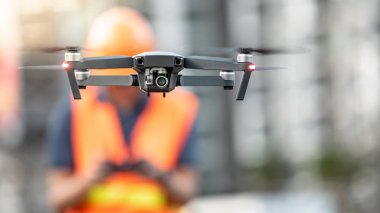 Asya mühendis adam ya da erkek işçi dron inşaat sitesi üzerinden uçan. İnsansız hava aracı (İHA) arazi için kullanarak ve inşaat mühendisliği proje sitesi anket oluşturma.