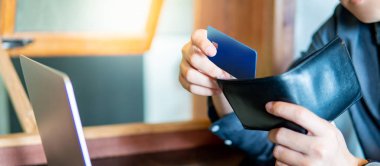 Erkek el kredi kartı cüzdanını koyarak. Kredi kartı için online alışveriş dizüstü bilgisayar kullanarak. Dijital ödeme ve nakitsiz toplum kavramları