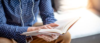 Kitap sayfada gösteren erkek ele. Divan kitaplığındaki kitap okuma öğrenci genç adam. Eğitim Araştırma ve kendi kendine çalışma. Gözden geçirme veya tarama. Dünya kitap günü concep