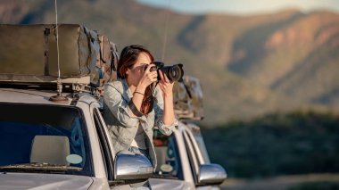 Genç Asyalı kadın gezgin ve araba penceresi alarak fotoğraf yolu üzerinde oturan fotoğrafçı Namibya Afrika gezisi. Seyahat fotoğraf kavramı