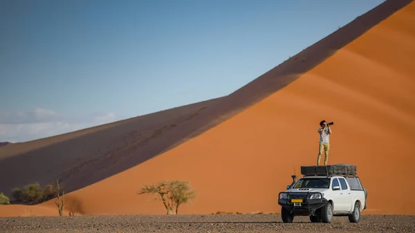年轻的亚洲男人旅行者和摄影师站在露营车附近橙色沙丘 沙漠公路旅行的概念 — 图库照片