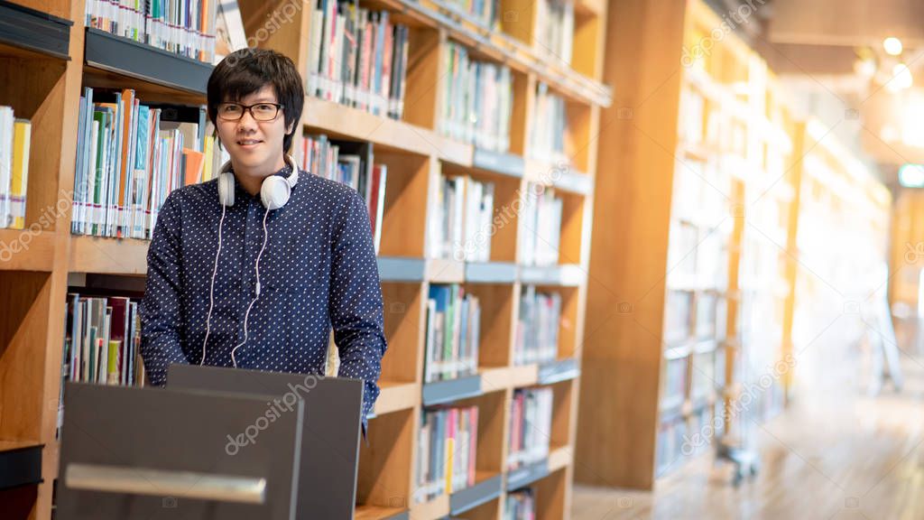 Young Asian man university student pushing book cart in college library finding textbook for education research. Bestseller collection in bookstore. Scholarship or educational opportunity concepts