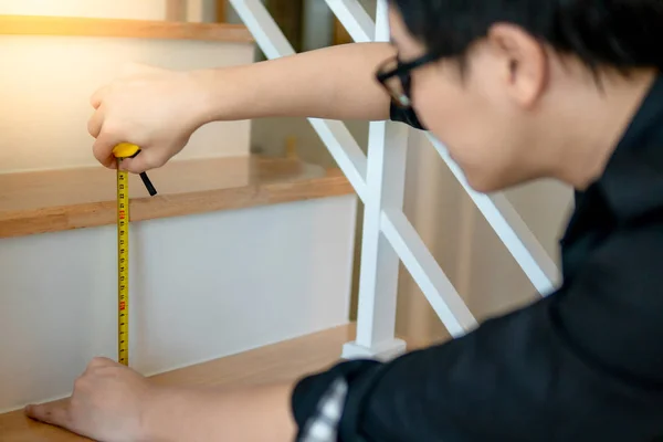 Азиатский рабочий с помощью рулетки на лестнице — стоковое фото