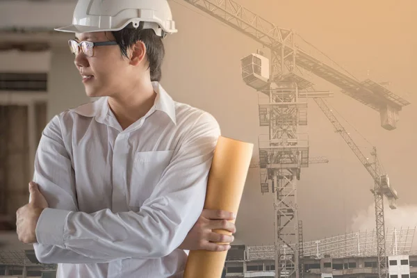 Asian male engineer holding blueprint at site
