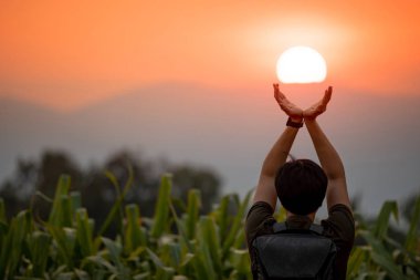 Asian man in corn field holding the sun clipart