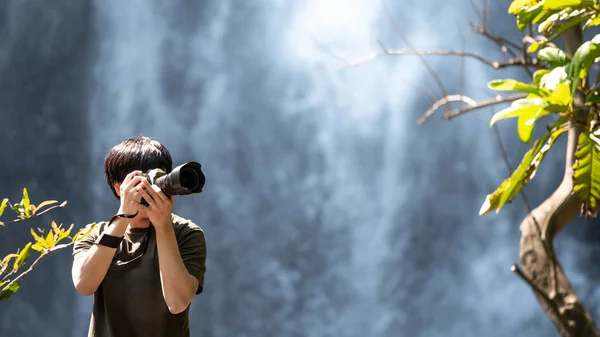 Азиатский путешественник фотографирует у водопада — стоковое фото