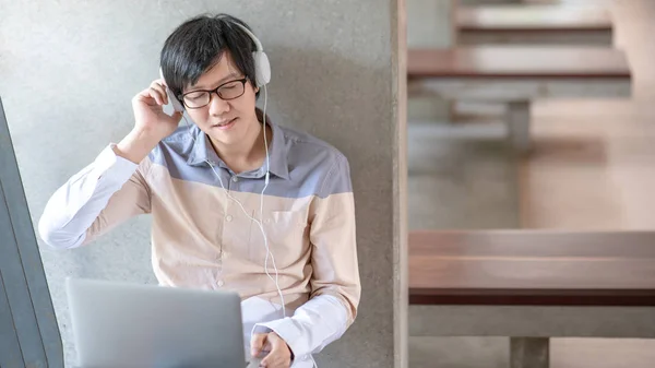 Asiático homem estudante ouvindo música usando laptop — Fotografia de Stock