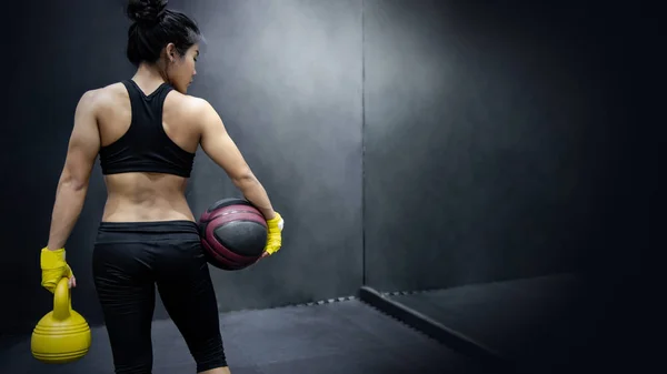 Азиатская девушка с баскетболом и гирями — стоковое фото