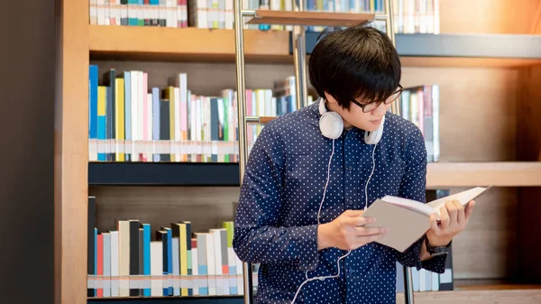 Asiático hombre estudiante lectura libro en biblioteca — Foto de Stock