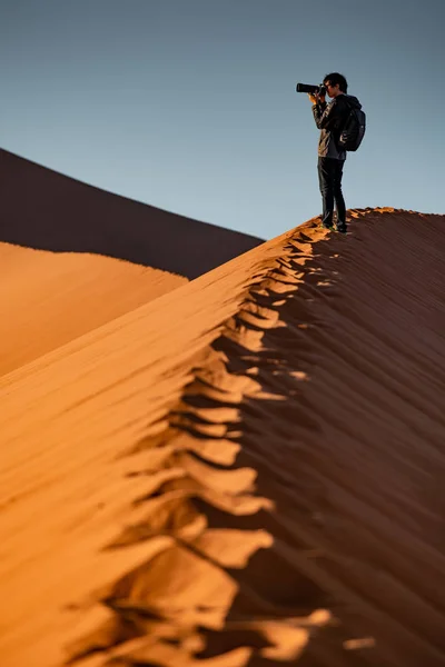 Мужчина-фотограф стоит на песчаной дюне — стоковое фото