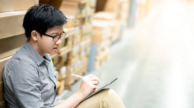 Asyalı adam depoda tablet üzerinde stok yapıyor