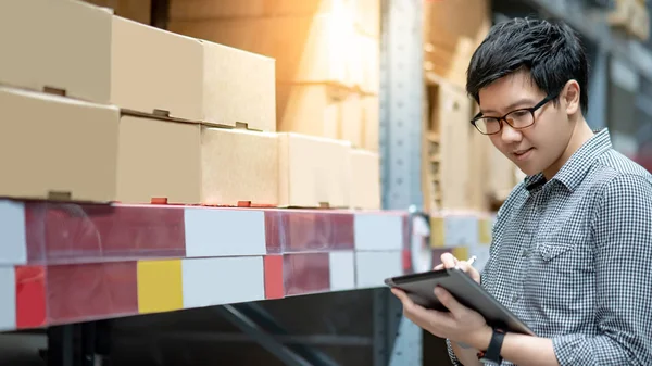 Asyalı adam depoda tablet üzerinde stok yapıyor
