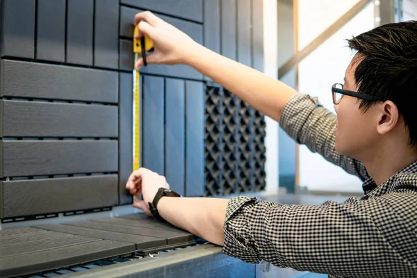 Asian man using tape measure on floor pavement