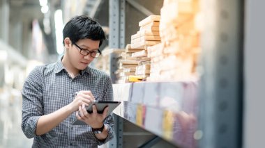 Asyalı adam depoda tablet üzerinde stok yapıyor