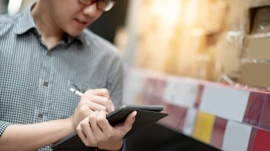 Asyalı adam depoda tablet üzerinde stok yapıyor