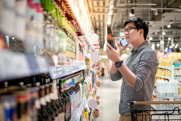 電話を使ったアジア人男性ショッピングビール — ストック写真