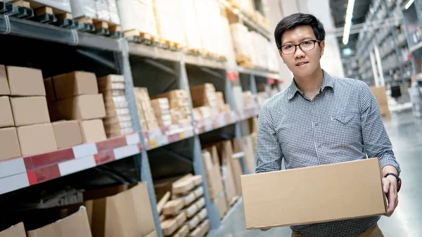 Hombre asiático llevando caja de cartón en almacén — Foto de Stock