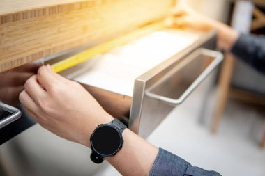 Asyalı adam çekmecede bant ölçüsü kullanarak