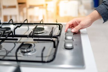 Erkek el, gaz sobasının düğmesini çeviriyor.