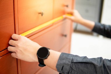 Dolap çekmecesinde bant ölçüsü kullanan erkek el