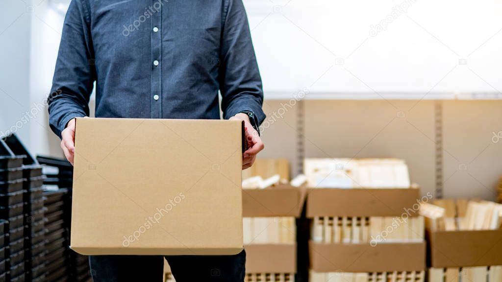 Courier man carrying box shopping in warehouse