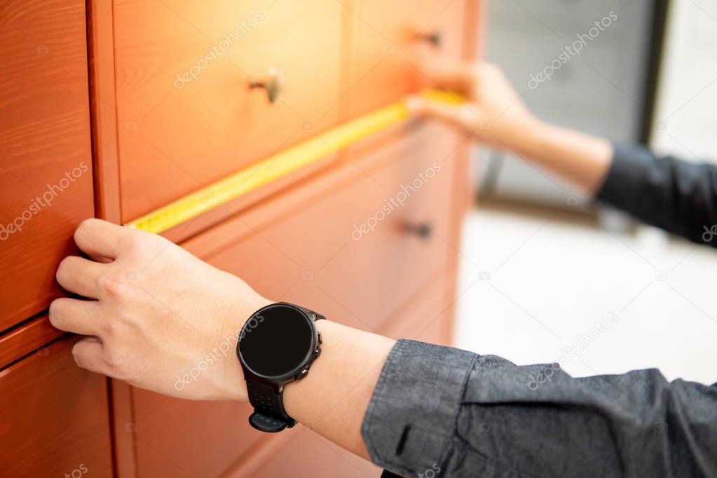 Male hand using tape measure on cabinet drawer
