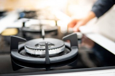 Erkek el, gaz sobasının düğmesini çeviriyor.