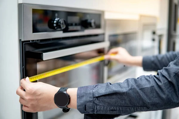 Mano masculina usando cinta métrica en el horno —  Fotos de Stock