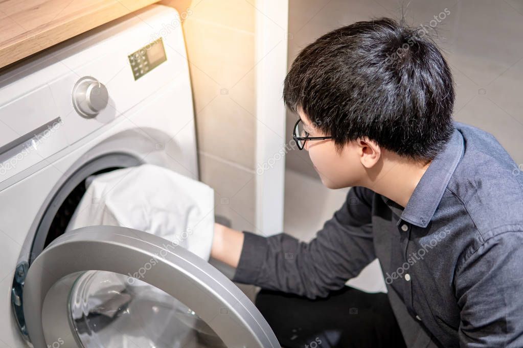 Asian man picking clothes from washing machine