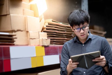 Asyalı adam depoda tablet üzerinde stok yapıyor